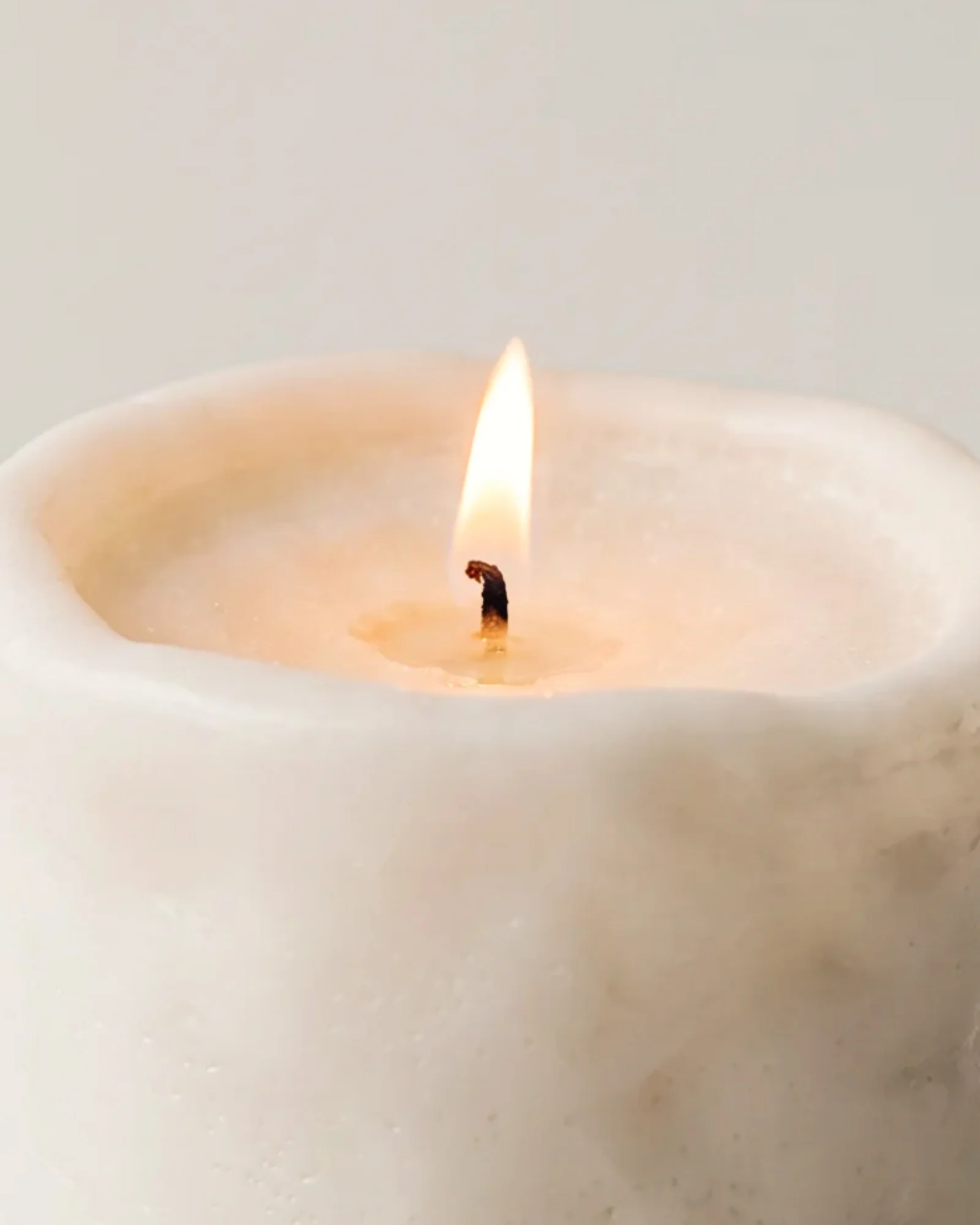 Close-up of the uneven rim and textured surface of a light-coloured Clay Cylinder candle