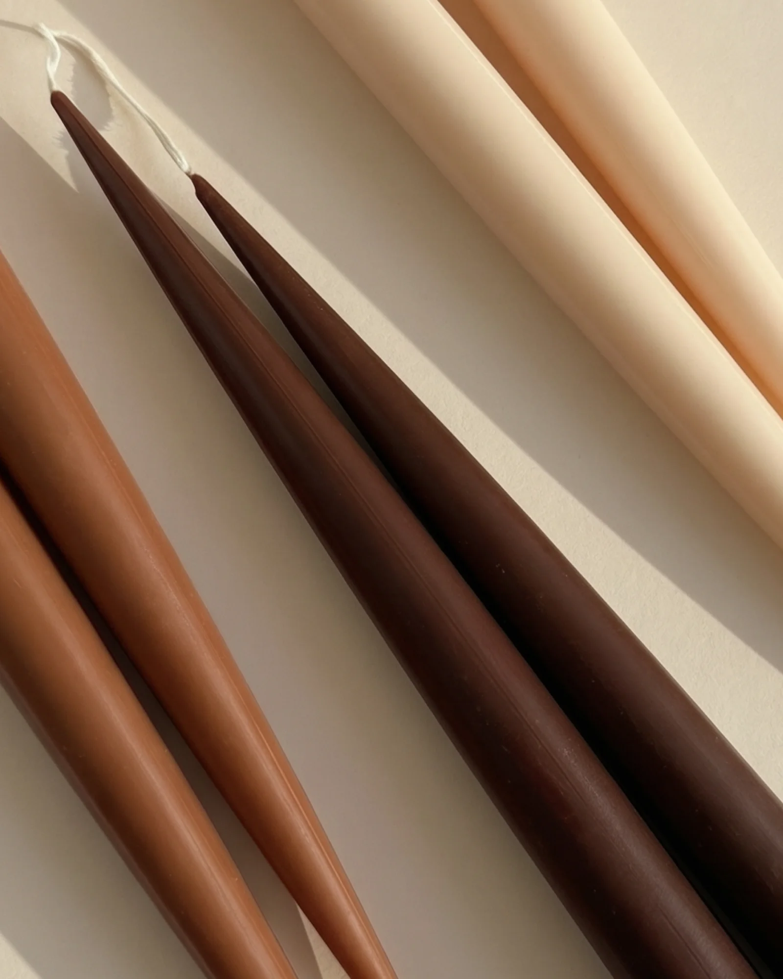 Close-up of ivory and brown Earthen Six taper candles in sunlight