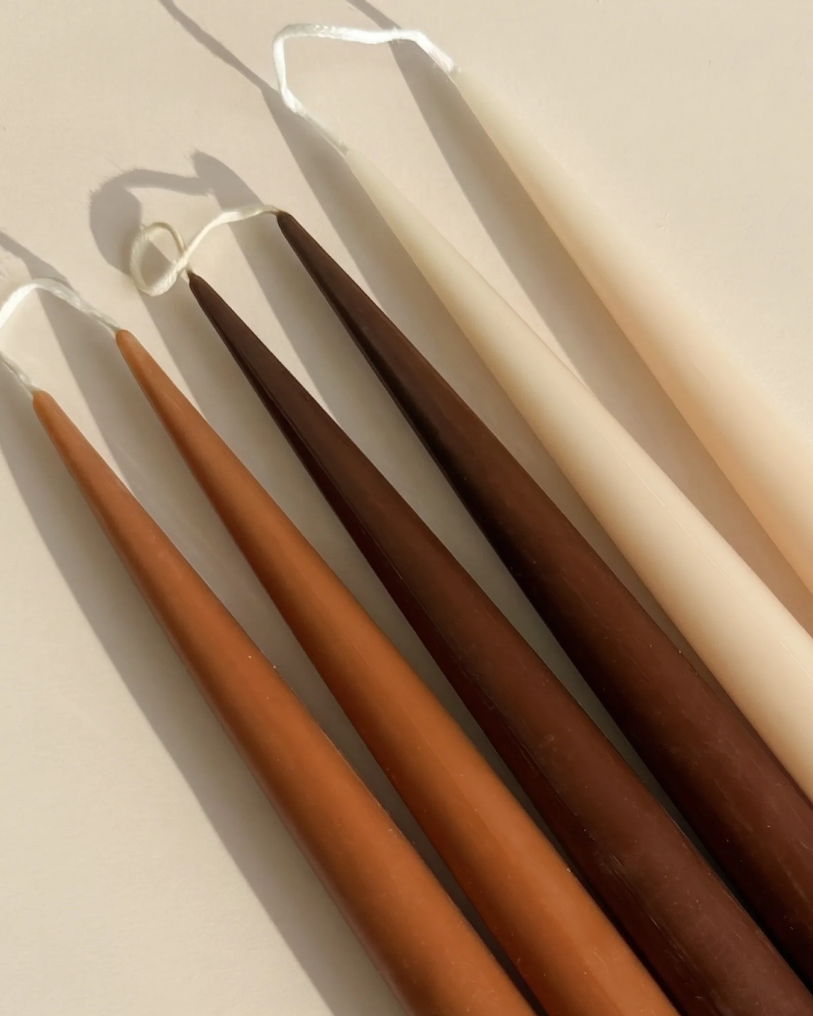 Earthen Six ivory and brown taper candles arranged diagonally
