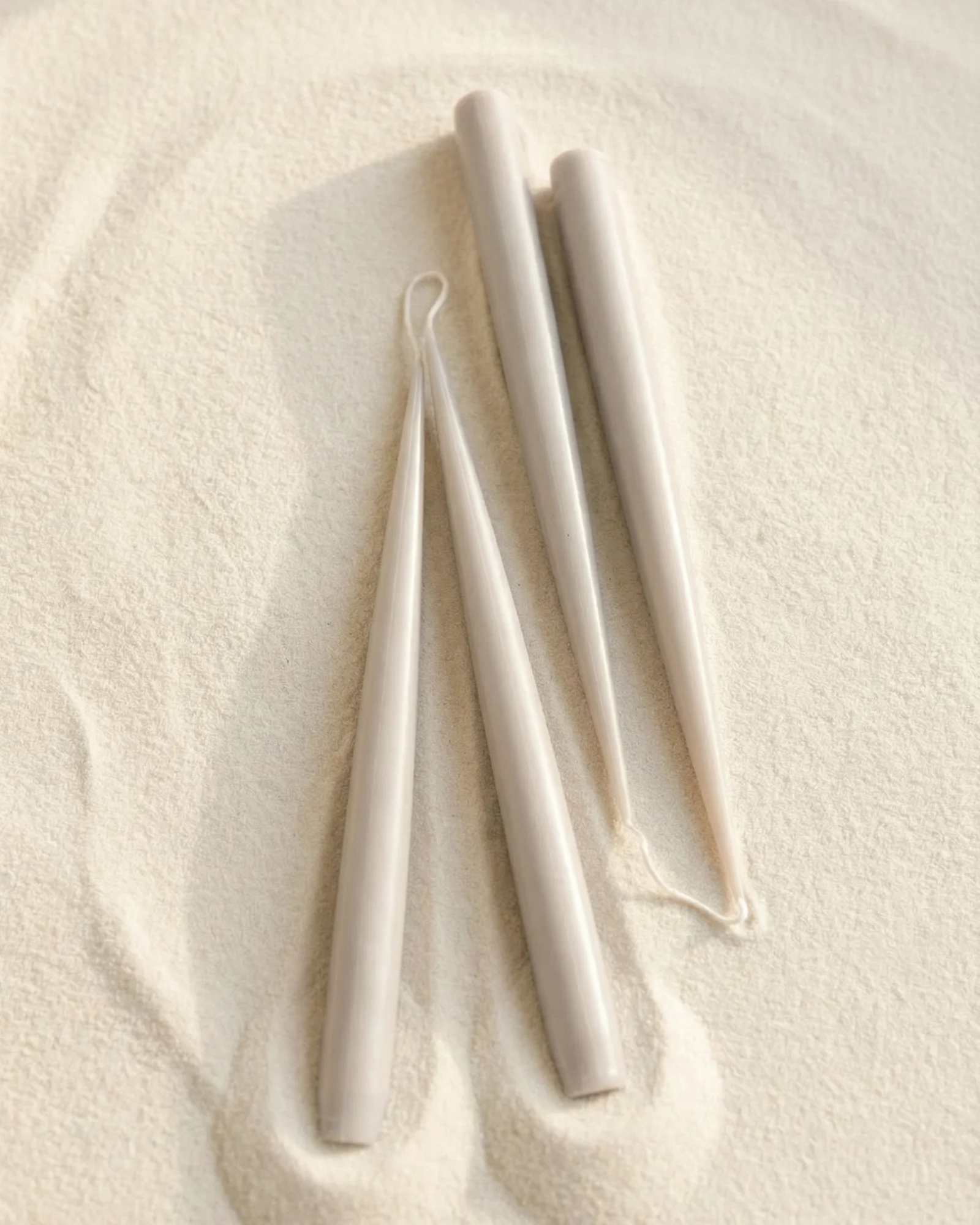 Sculptural candles standing upright with a smooth, minimal form.