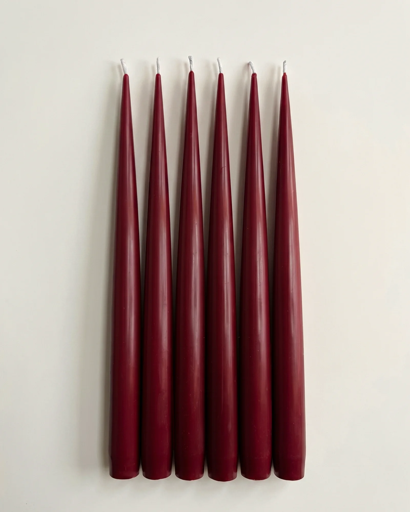 Six Vivid Red taper candles arranged side by side