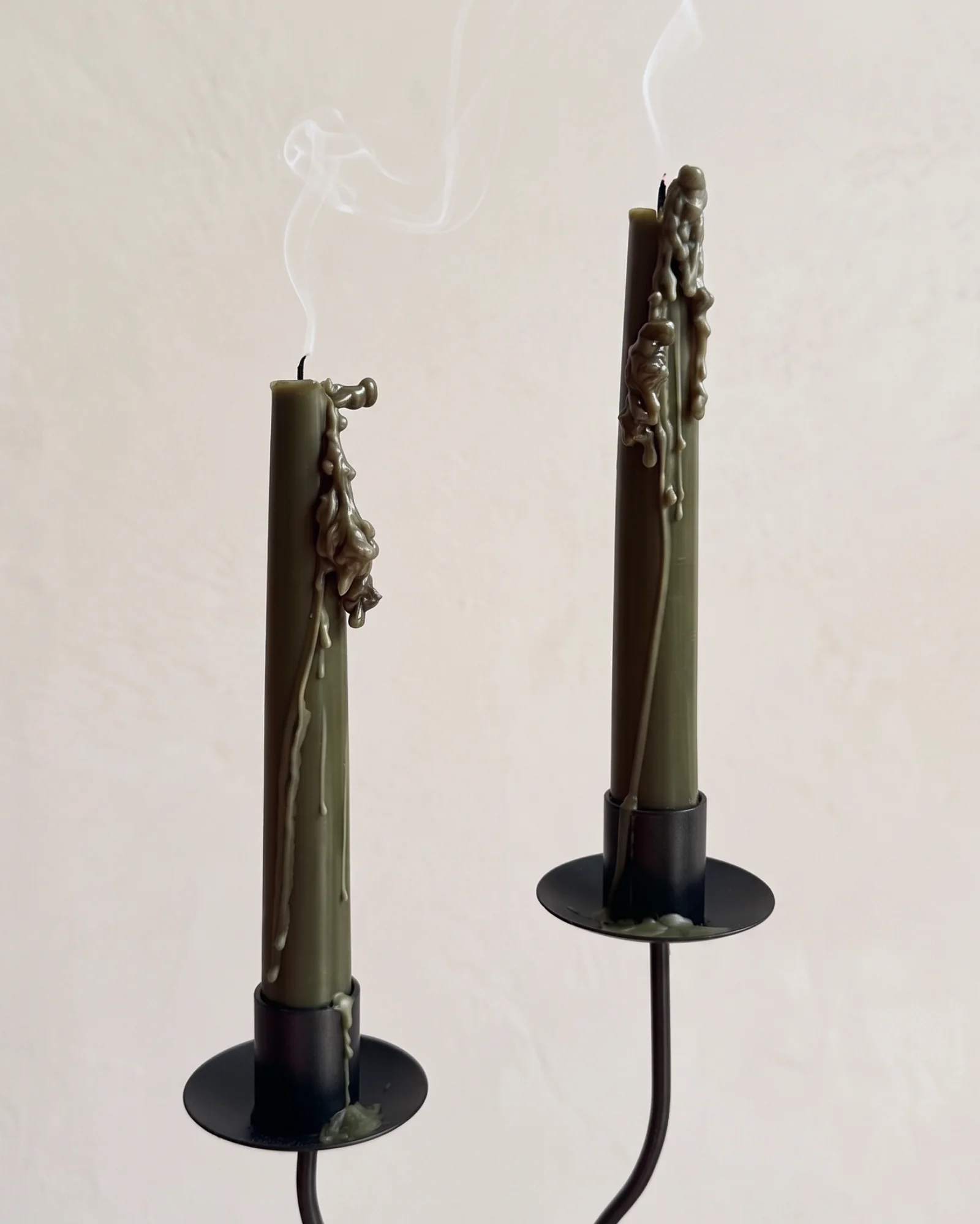Two extinguished Deep Pine taper candles with melted wax and rising smoke