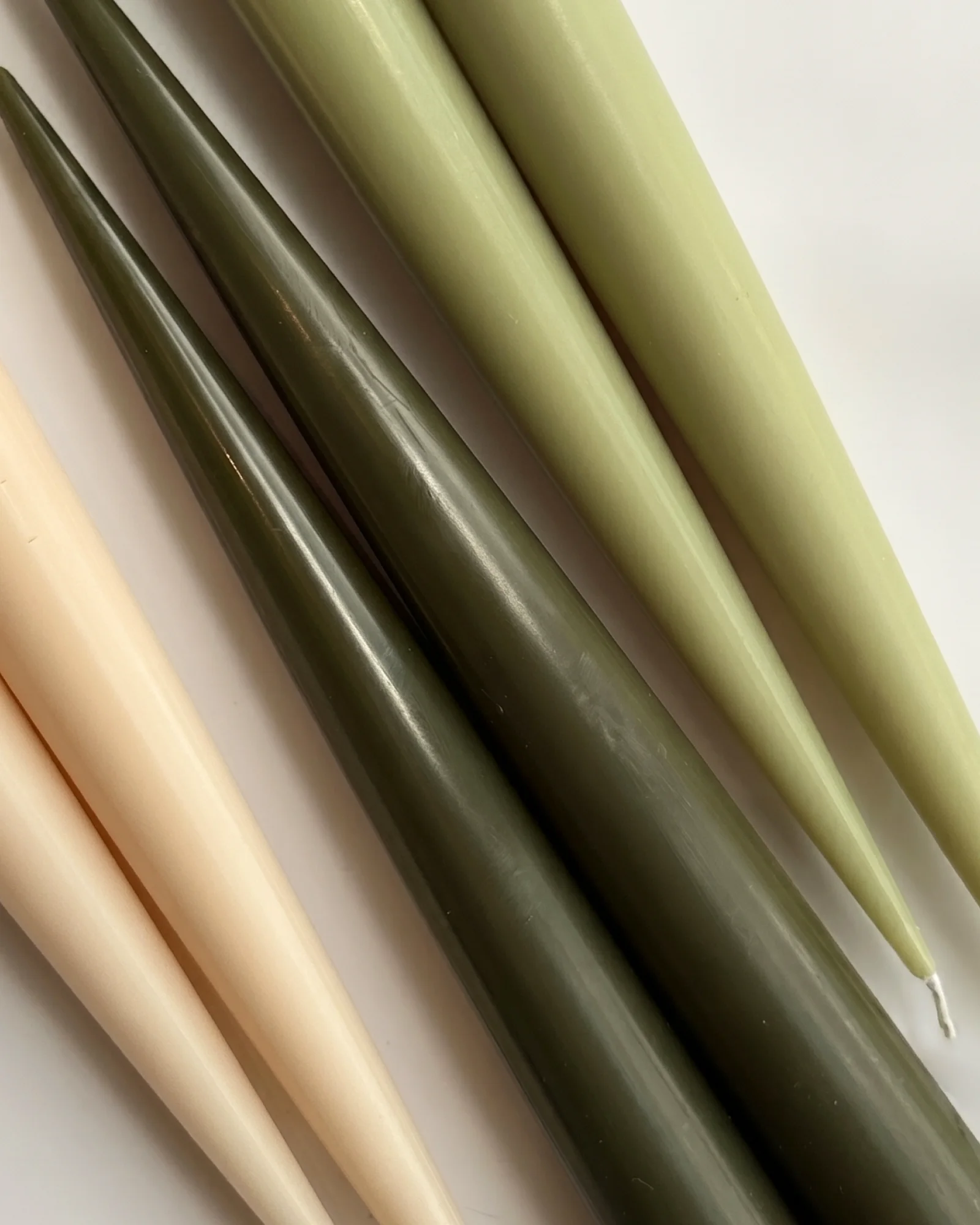 Close-up of Forest Six taper candles in ivory, deep green and pale green