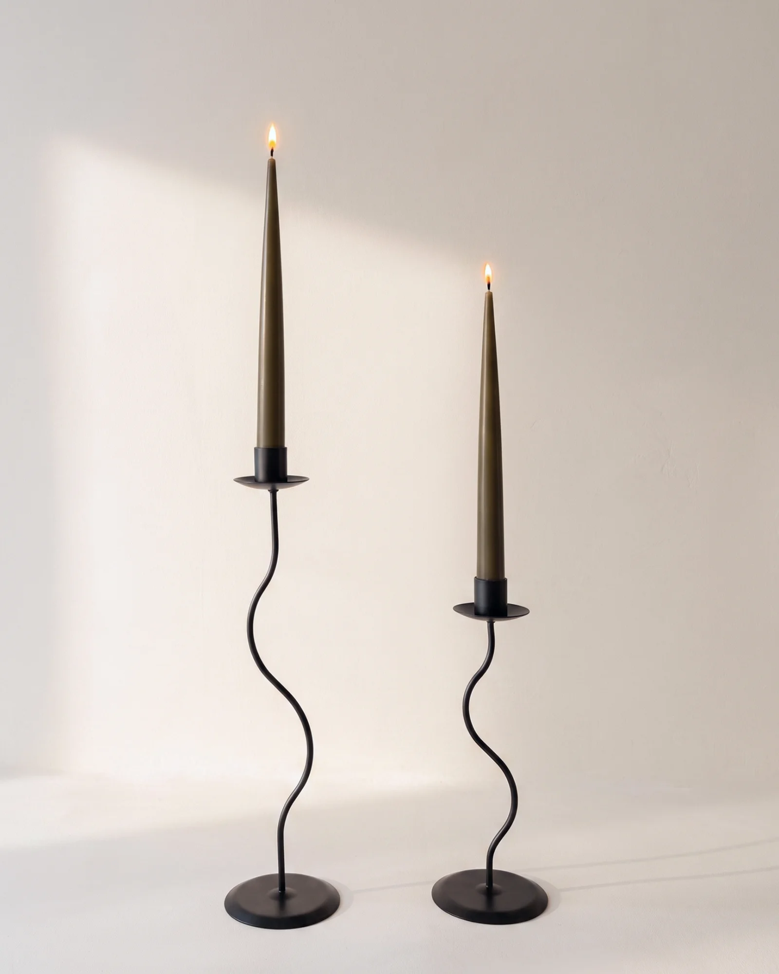Tall and short black Wave Candle Holders with lit olive taper candles