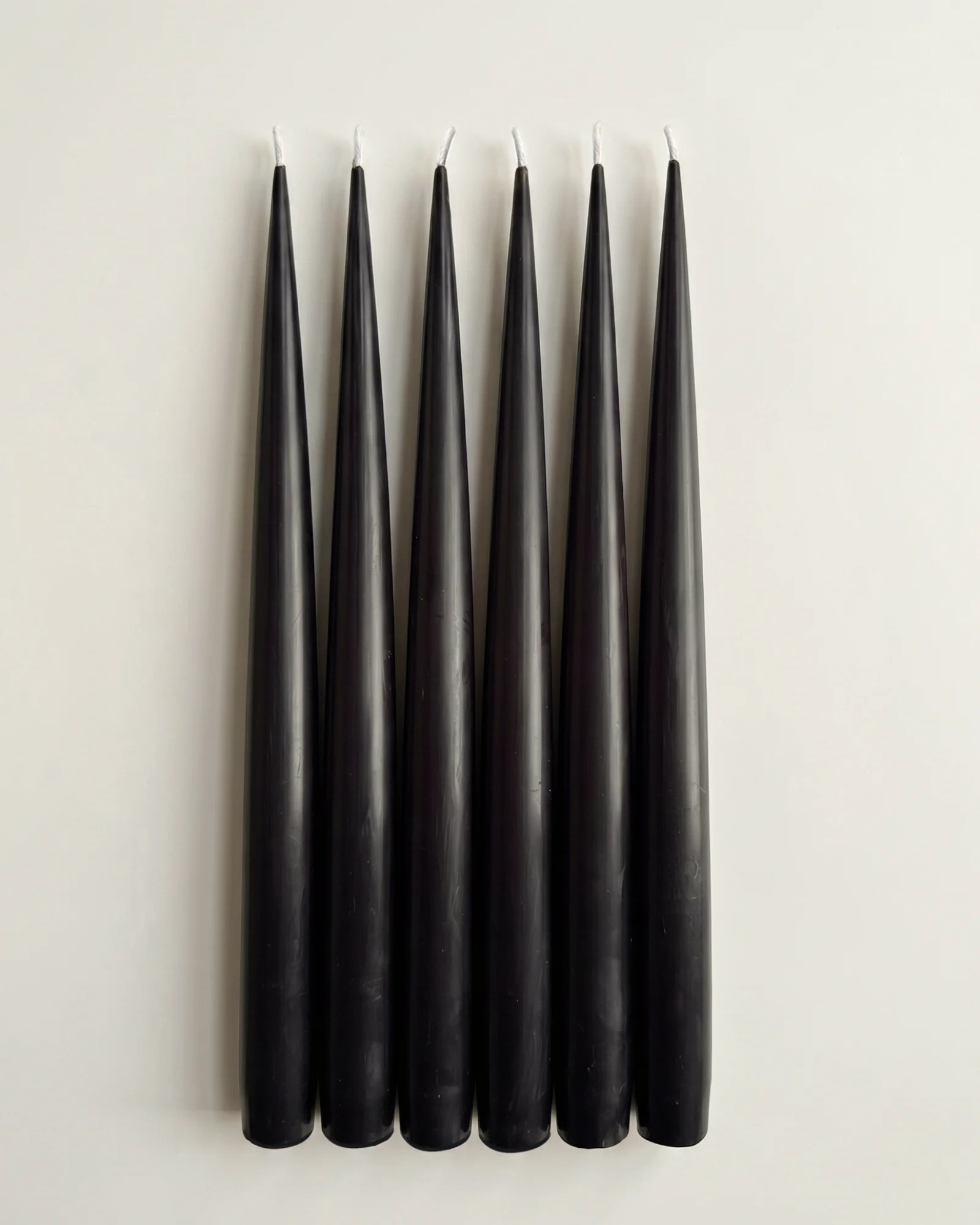 Six Jet Black taper candles arranged side by side