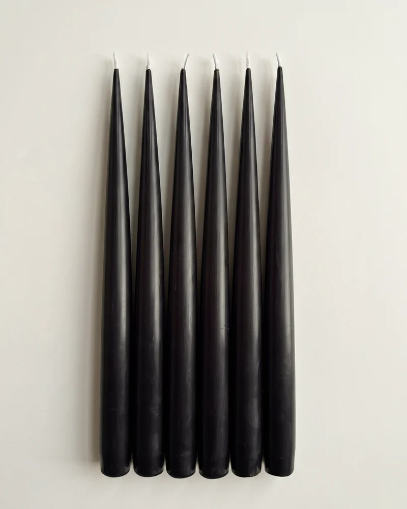 Six Jet Black taper candles arranged side by side