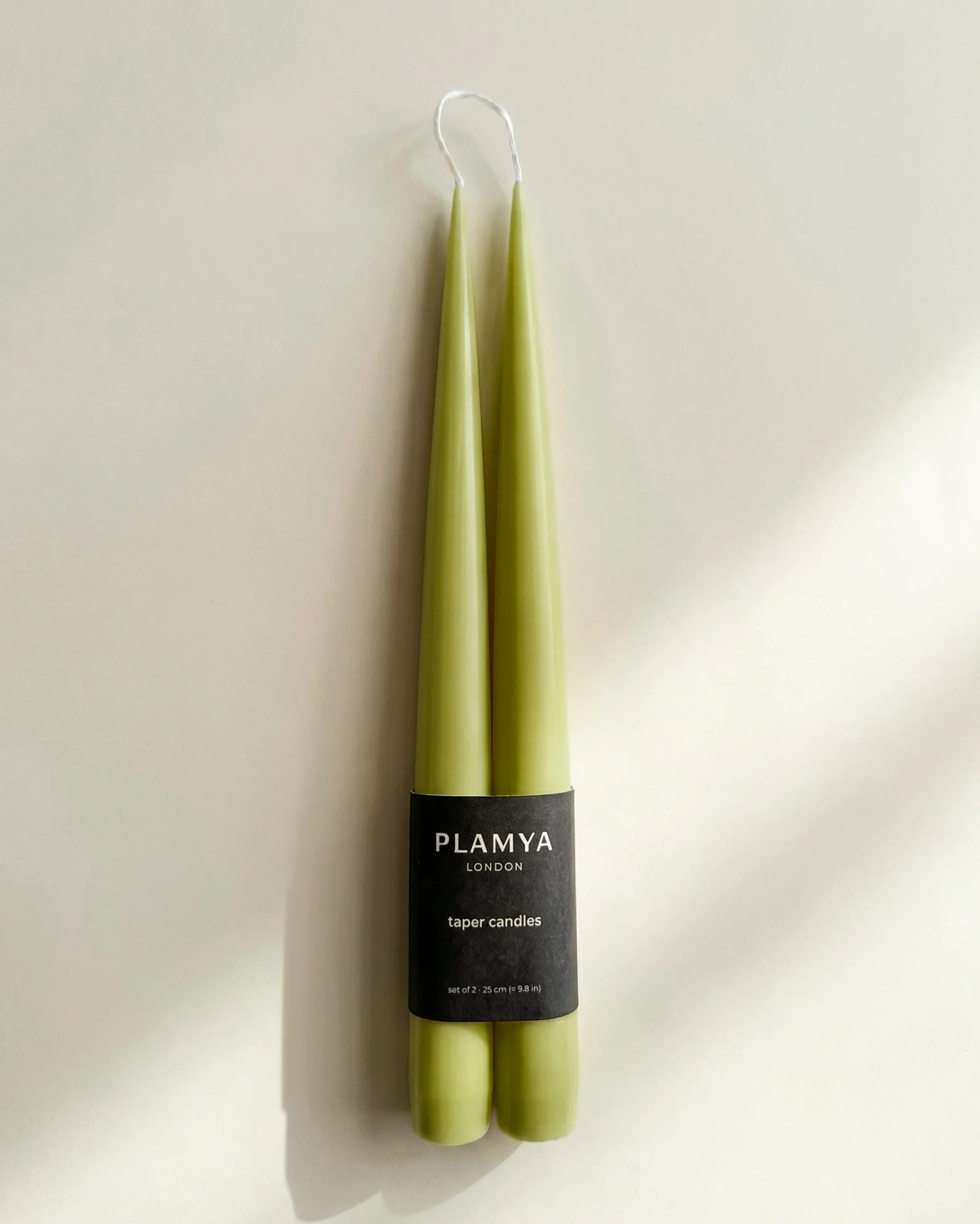 Matcha taper candle pair wrapped with a black PLAMYA paper band